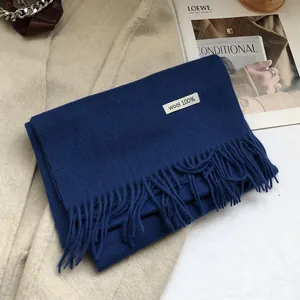 Detail of 100% Australian wool scarf with tassels and fabric label on stylish coat