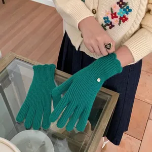 Detailed knit texture of green winter gloves with stylish scalloped cuffs and gold charm