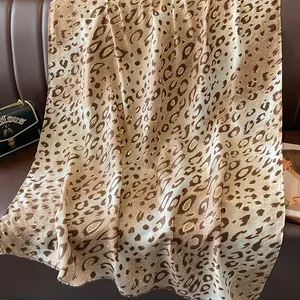 Écharpe léopard caramel avec détails dorés sur un fond de cuir luxueux