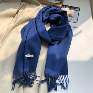 Detail of dark blue 100% wool scarf showing soft knit texture and long fringe tassels