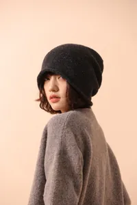 Detail of grey wool knit beanie with colorful speckles worn by a model in a studio setting