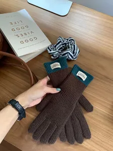 Close-up of winter knit gloves with dark brown body and contrast blue ribbed cuffs