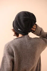 Detailed texture of dark grey wool knit beanie with colorful fiber flecks on a model