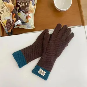 Detail of knit gloves with peacock blue ribbed cuffs and woven brand patch label