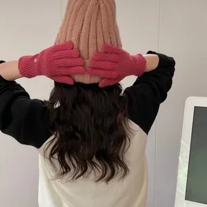 Detail of warm pink knit touchscreen gloves and cozy ribbed beanie on a model