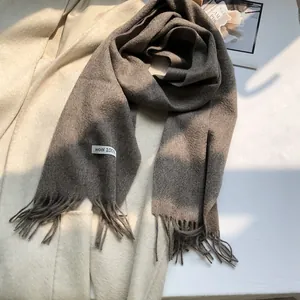 Close-up of the 100% wool label and fringe detail on the brown gradient scarf