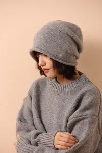 Close-up of a grey 100% wool knit beanie with rolled edge texture worn by a model