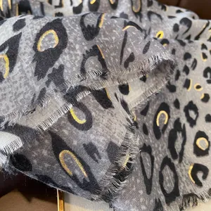 Détail d'une écharpe léopard avec touches de dorure métallique et bords frangés