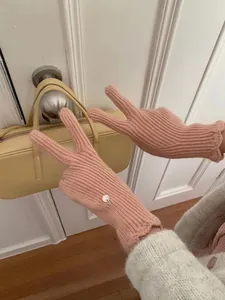 Pink knit gloves with vertical ribs, wavy lace cuffs and a silver metal pendant