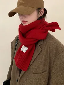 Detail showing the 100% wool label on a thick red knit scarf with winter texture