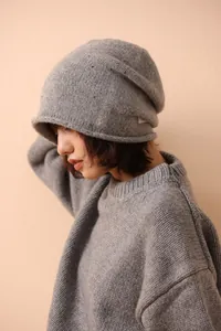 Close-up detail of grey pure wool knit beanie showing textured yarn and woven side label