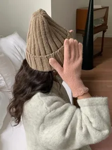 Detail of pink knitted touch screen gloves paired with a warm beige ribbed winter hat