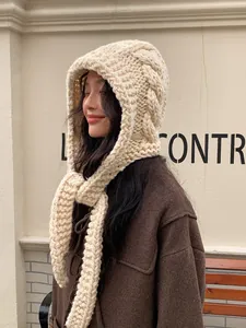 Detail of chunky cable-knit balaclava in cream with handmade texture and side leather tag
