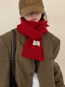 Detailed close-up of 100% Australian wool red knit scarf with ribbed texture and woven tag