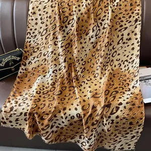 Détail d'un foulard en soie à motif léopard avec éclat satiné sur un canapé en cuir
