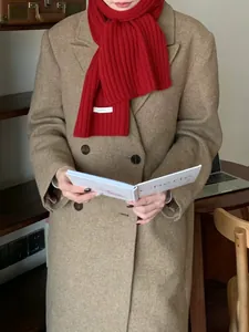 Detail of red thick knit wool scarf paired with a brown double-breasted coat in autumn style