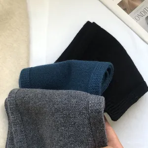 Close-up of three knitted 100% wool leg warmers in black, navy blue and grey colors