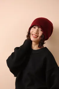 Detail of burgundy wool knit beanie paired with a black oversized sweater on a model