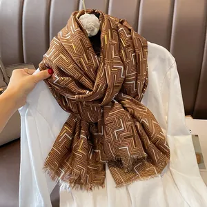 Close-up of golden geometric labyrinth patterns and tassel edges on a brown winter scarf