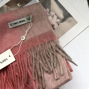 Detailstruktur des rosa-braun karierten Schals aus 100 % Wolle mit weichen Fransen und Label