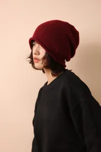 Detailed knit texture of dark red wool beanie with colorful specks and rolled edge design