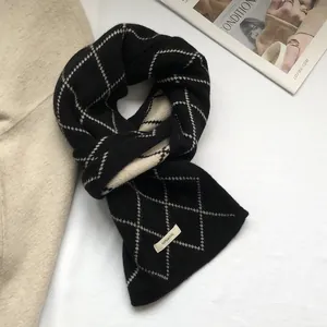 Close-up of 100% wool label on black and white diamond pattern knitted scarf