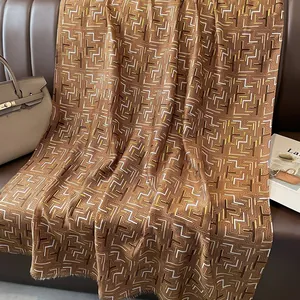 Close-up of geometric pattern scarf with gold foil accents and soft fringe texture