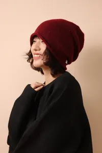 Detail of dark red wool beanie with colorful tweed flecks and white stitched patch