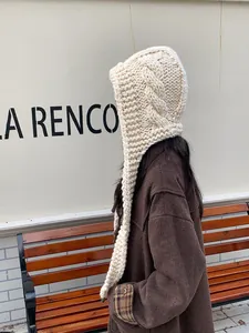 Close-up of cable knit texture on cream thick winter balaclava with long earflaps