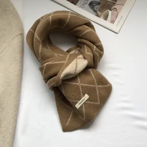 Close-up of 100% wool knit scarf featuring brown diamond pattern and fabric care label