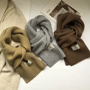 Close-up of three 100% pure wool scarves in camel, gray and brown with material tags