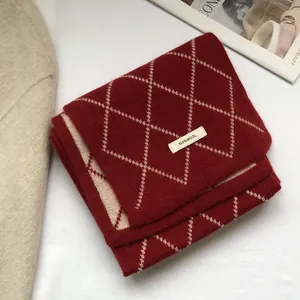 Macro shot of 100% wool red and white diamond pattern knitted scarf with textile tag
