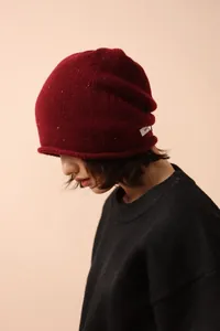 Detail of 100% pure wool knit beanie showing dark red fabric texture and brand label
