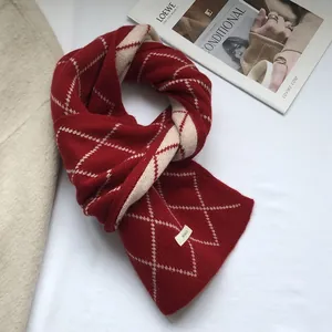 Detailed texture of burgundy diamond pattern knitted wool scarf with branded label