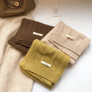 Detailed cable knit texture of 100% wool scarves in brown, beige and mustard yellow colors