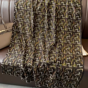 Detail of soft winter scarf with gold foil geometric patterns on leather sofa