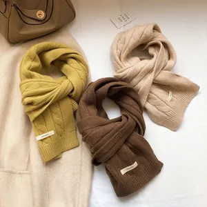 Three 100% wool knit cable scarves in mustard, chocolate, and cream white displayed flat