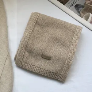 Close-up of beige 100% Australian wool scarf showing soft knit texture and brand label