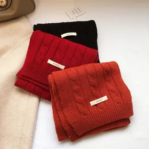 Detailed knit texture of 100% wool scarves in black, red, and caramel orange colors