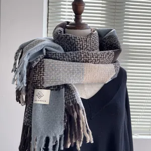 Close-up of thick blue plaid scarf showing houndstooth patterns and long tassel fringe