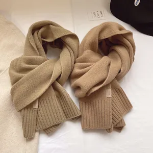 Close-up of warm camel knit 100% wool scarf featuring a woven label and cozy texture