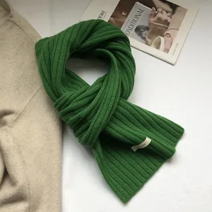 Detail of the 100% wool ribbed scarf in emerald green with a premium material label