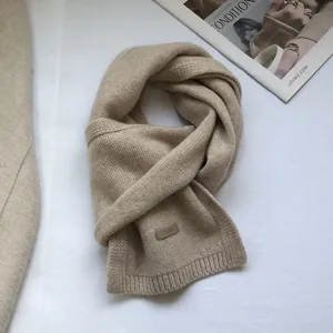 Detail of 100% Australian wool scarf featuring a leather label and soft knitted texture