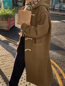 Street style view of a hooded wool coat with toggle buttons and a yellow plaid scarf