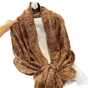Winter cotton linen scarf with gold geometric pattern and fringe details on white shirt