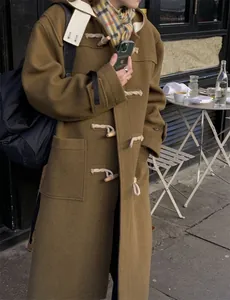 Detail of olive green wool coat featuring classic horn buttons and front patch pockets