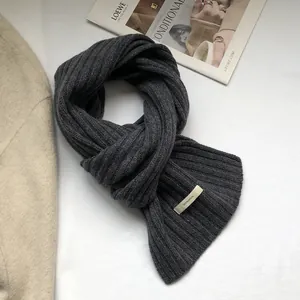 Close-up of the 100% wool label on a thick dark grey ribbed knit scarf for winter