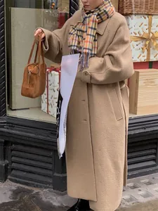 Detail of a wool plaid scarf paired with a camel oversized coat and a brown tote bag
