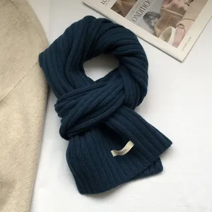 Detail of navy blue 100% wool scarf with chunky rib knit texture and soft material tag