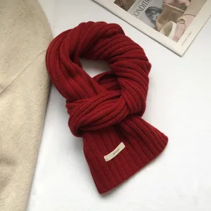 Detailed texture of thick red 100% wool scarf with ribbed knit pattern and fabric label